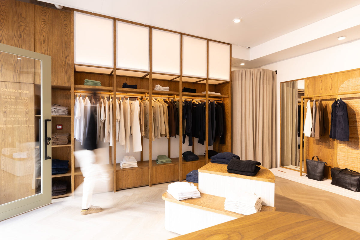 Wide view of Ogun’s flagship at 7 Park Road, with oak joinery, tiled display tables and soft light.